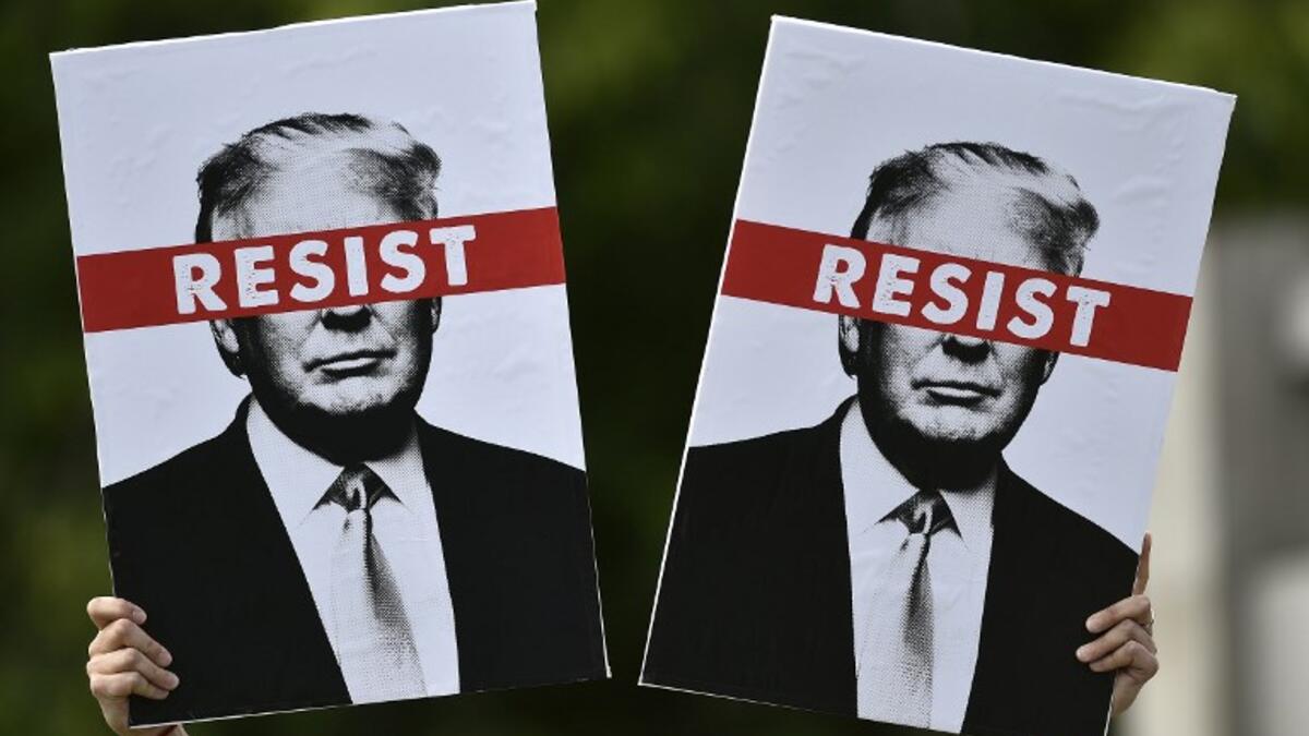 A protestor holds placards prior to the Scotland United Against Trump march through the streets of Edinburgh, Scotland on July 14, 2018, on the third day of US President Donald Trump's four-day UK visit. (NEIL HANNA / AFP)
