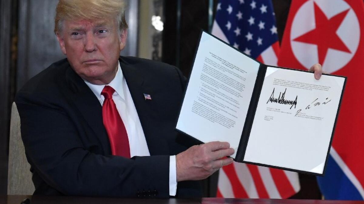 US President Donald Trump holds up a document signed by him and North Korea's leader Kim Jong Un following a signing ceremony during their historic US-North Korea summit, at the Capella Hotel on Sentosa island in Singapore on June 12, 2018. (SAUL LOEB / AFP)