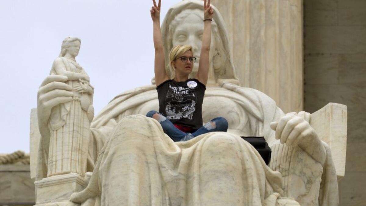 Demonstrator Jessica Campbell-Swanson of Denver, sits on the lap of the "Contemplation of Justice" statue as protestors protesting against the appointment of Supreme Court nominee Brett Kavanaugh at Capitol Hill in Washington DC, on October 6, 2018. (Jose Luis Magana / AFP)