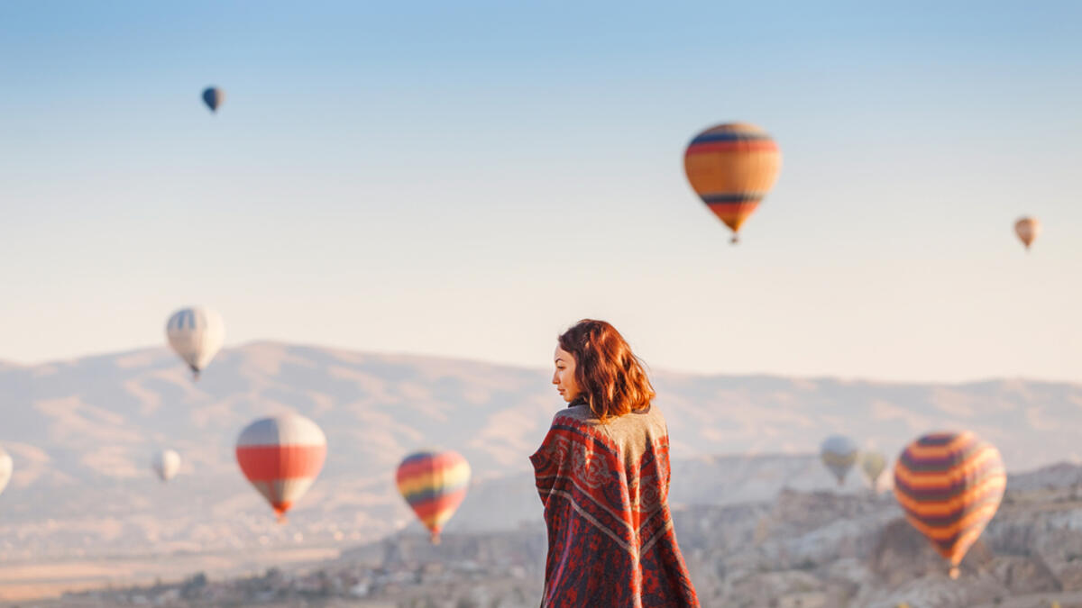 A tourist on a mountain top enjoying wonderful view of the sunrise and balloons in Cappadocia (Shutterstock/File Photo)
