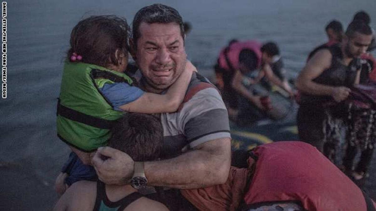 لاجئ يحتضن أولاده خلال بكائه بفرحة وصول قاربهم إلى إحدى الجزر اليونانية.