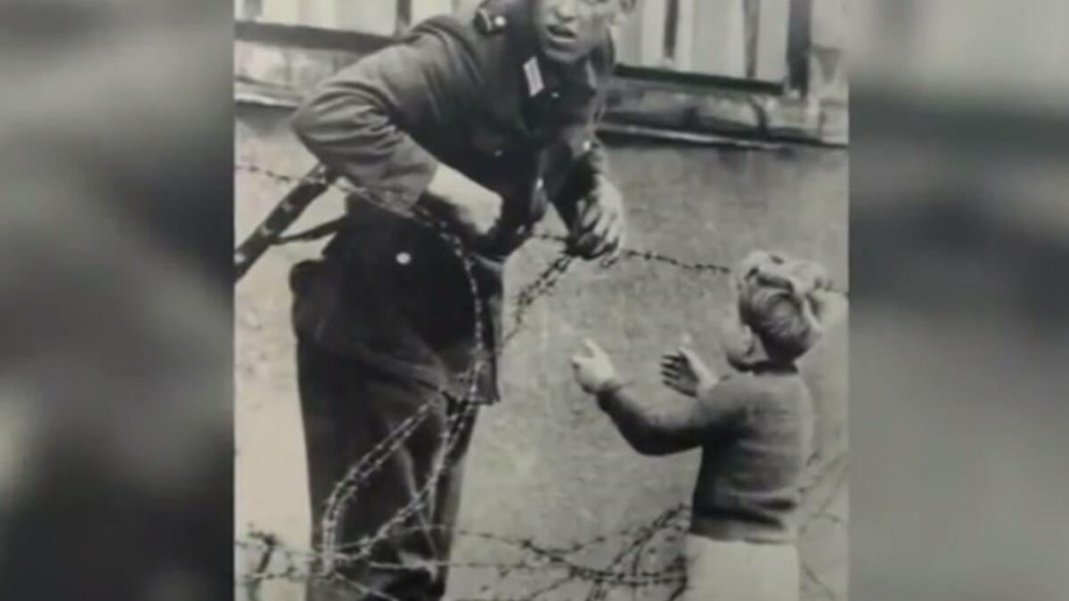 صورة لجندي من الضفة الشرقية يحاول مساعدة طفل من الضفة الغربية لألمانيا على اجتياز جدار برلين، حيث تظهر الصورة لهفة الطفل بالعودة لأهله وخوف الجندي من ضبطه في حالته الإنسانية، والذي كان لديه تعليمات آنذاك بقتل متسلقي الجدار.