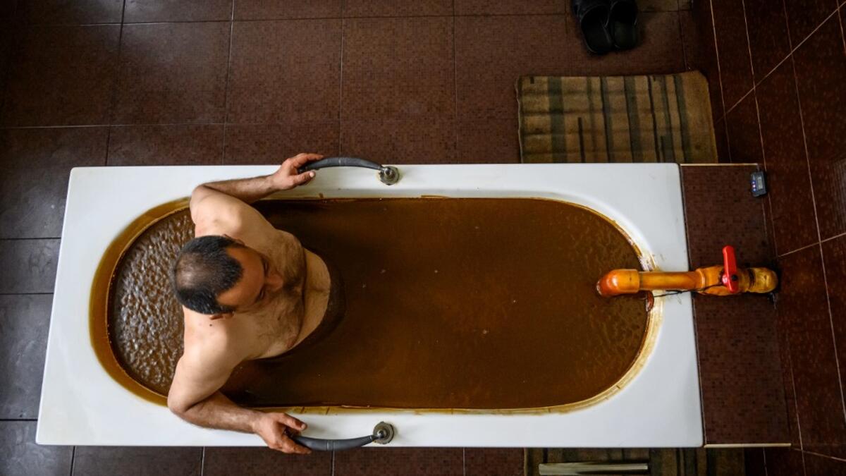 A man bathes in a tub filled with Naftalan crude oil during a treatment session at Sehirli Naftalan Health Center, some 300 kilometres (186 miles) from capital Baku, on March 21, 2019. Immersed up to her neck in crude oil, a Russian woman suffering from joint disease smiles in delight, confident that the treatment at a spa in northwestern Azerbaijan will cure her painful condition.  Mladen ANTONOV / AFP
