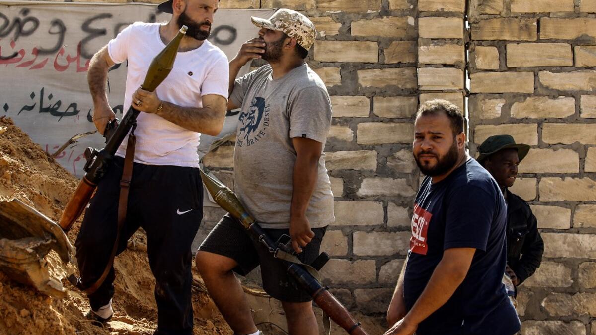 Libyan fighters loyal to the Government of National Accord (GNA) hold rocket-propelled grenade (RPG) launchers as they stand behind a dirt barrier during clashes with forces loyal to strongman Khalifa Haftar south of the capital Tripoli's suburb of Ain Zara, on April 10, 2019. Mahmud TURKIA / AFP