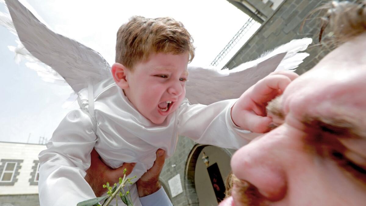 A toddler in angel costume pinches a man as Catholic believers gather outside Greek-Melkite Patriarchal Cathedral of the Dormition of Our Lady to mark Palm Sunday in the capital Damascus in Bab Sharki, Old Damascus on April 14, 2019.  LOUAI BESHARA / AFP