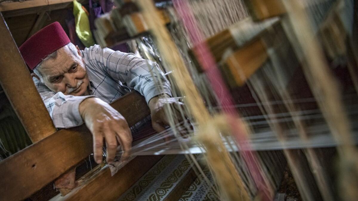 Abdelkader Ouazzani, the last of Morocco's brocade master weavers, displays tapestry at his workshop in the old city of Fez on April 10, 2019. His skilfull hands intricately create shimmering silk fabrics, enhanced with gold or silver thread, for bridal jewellery, designer creations or high-end furnishings. FADEL SENNA / AFP