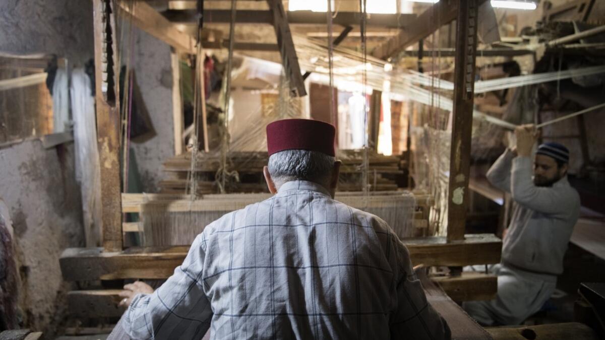 Abdelkader Ouazzani, the last of Morocco's brocade master weavers, displays tapestry at his workshop in the old city of Fez on April 10, 2019. His skilfull hands intricately create shimmering silk fabrics, enhanced with gold or silver thread, for bridal jewellery, designer creations or high-end furnishings. FADEL SENNA / AFP