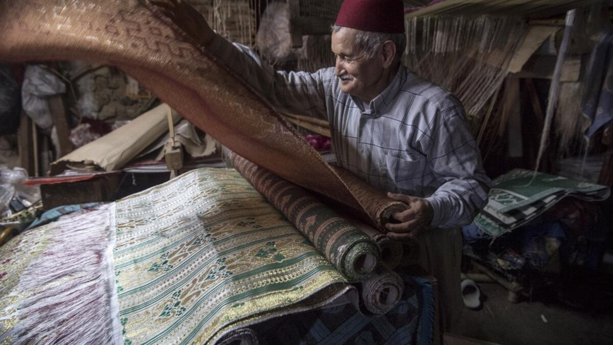 Abdelkader Ouazzani, the last of Morocco's brocade master weavers, displays tapestry at his workshop in the old city of Fez on April 10, 2019. His skilfull hands intricately create shimmering silk fabrics, enhanced with gold or silver thread, for bridal jewellery, designer creations or high-end furnishings. FADEL SENNA / AFP