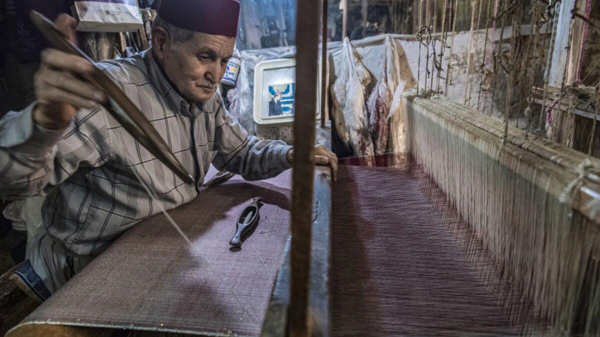 Abdelkader Ouazzani, the last of Morocco's brocade master weavers, displays tapestry at his workshop in the old city of Fez on April 10, 2019. His skilfull hands intricately create shimmering silk fabrics, enhanced with gold or silver thread, for bridal jewellery, designer creations or high-end furnishings. FADEL SENNA / AFP