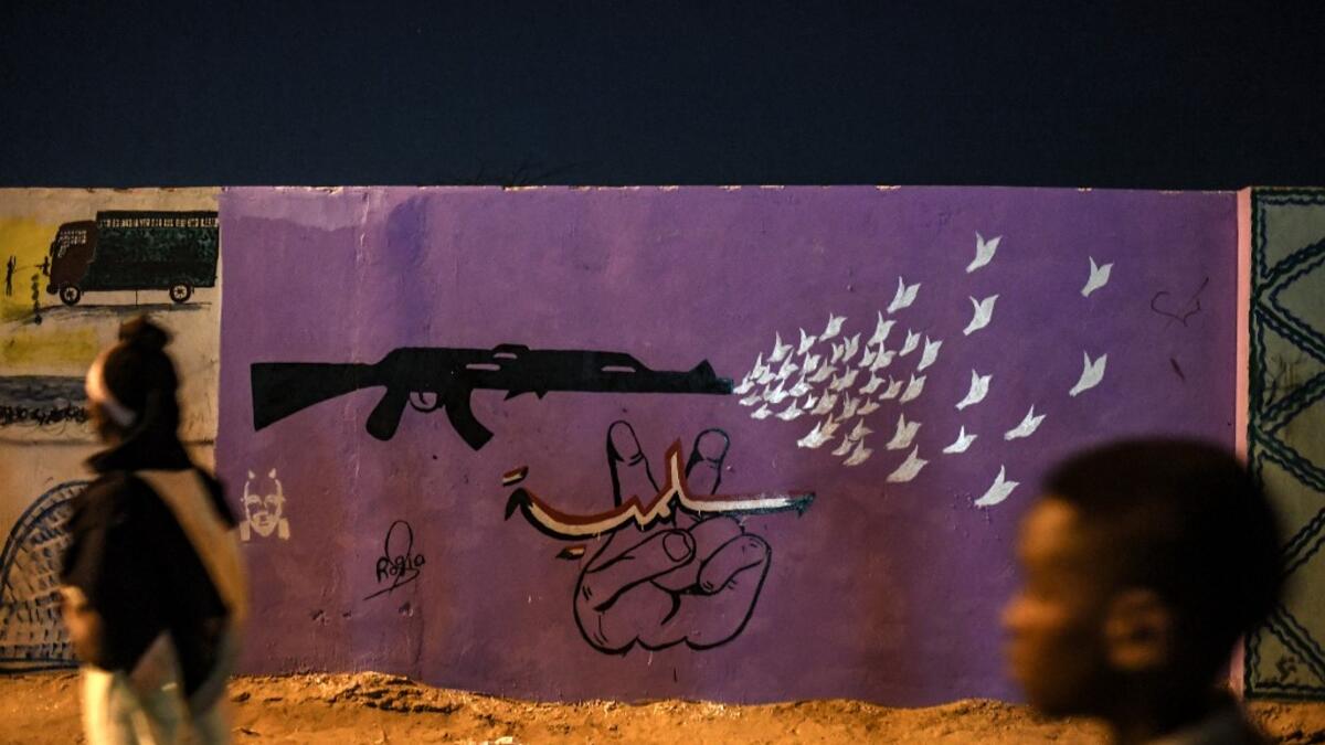 Sudanese protestors walk in front of a recently painted mural during a protest outside the army complex in the capital Khartoum. OZAN KOSE / AFP