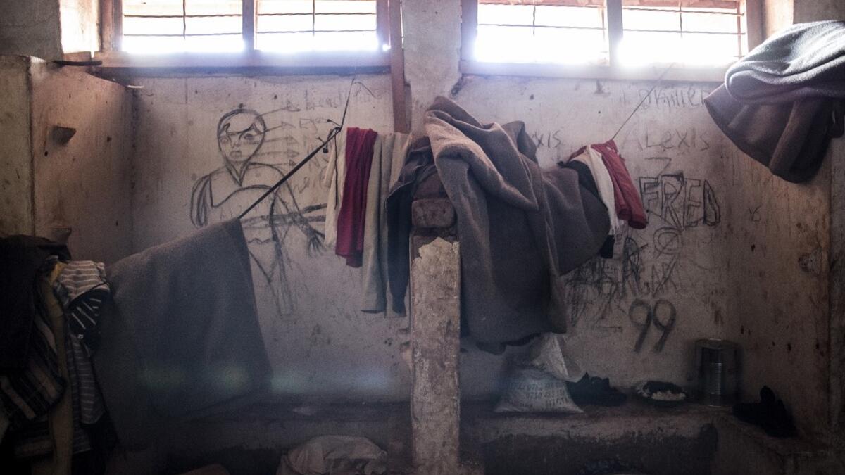 This picture shows blankets and clothes of South Sudanese refugees hanging in front of a wall filled with drawings and writings depicting scenes from home in a refugee transition camp for refugees who have just arrived in Aru. JOHN WESSELS / AFP