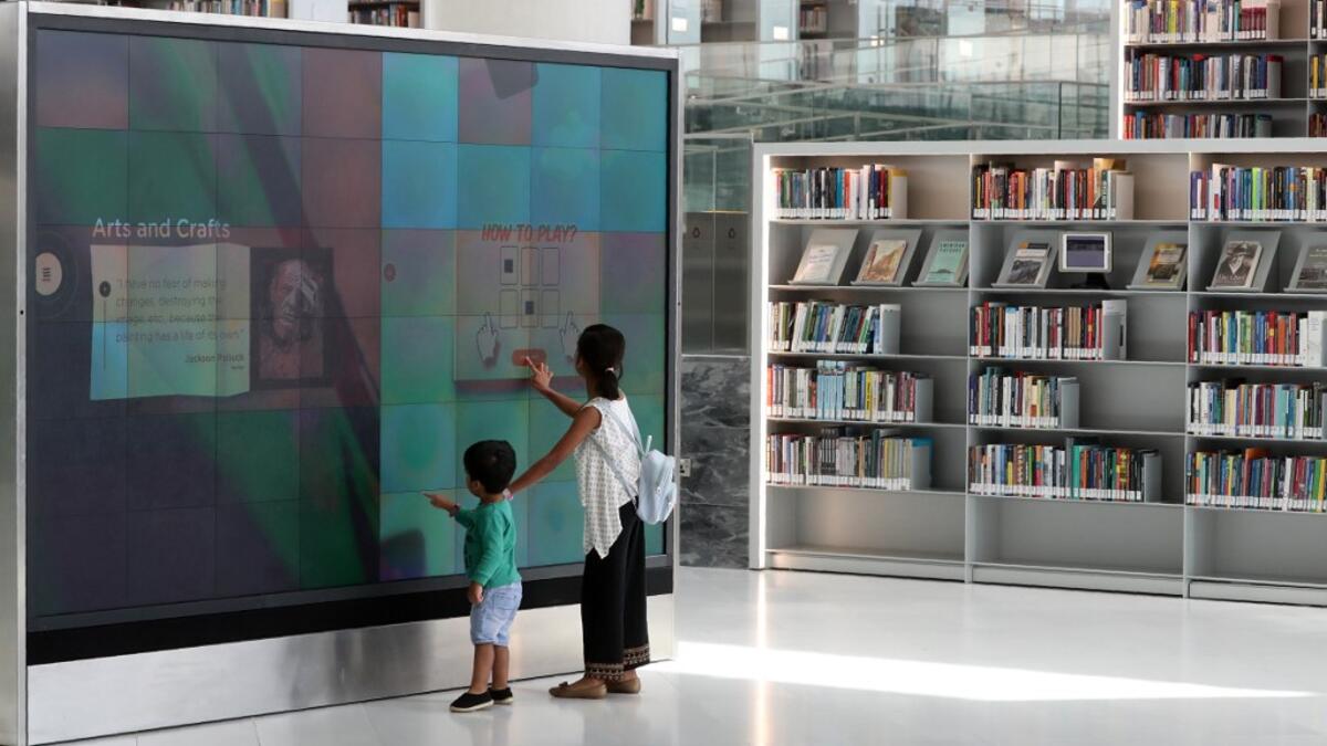 A girl and a boy use a giant interactive display screen at the Qatar National Library in the capital Doha.  KARIM JAAFAR / AFP