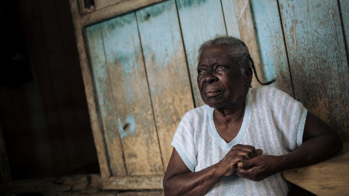 Agida Lucia, 89, sits in front of her house in the roca Agostinho Neto, an abandoned cocoa plantation of Sao Tome and Principe on May 29, 2019. Alexis HUGUET / AFP