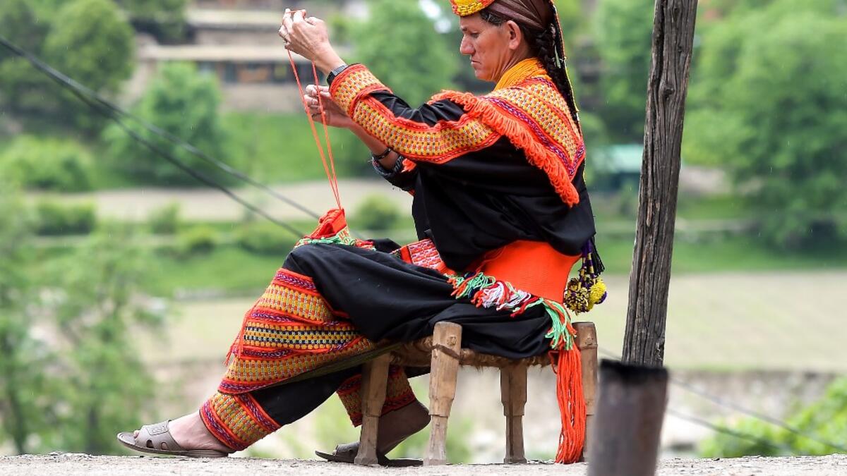 In this picture a Kalash woman wearing a traditional dress knits clothes outside her house after celebrating 'Joshi', a festival to welcome the arrival of spring, at Bumburate village in the mountainous valleys in northern Pakistan. AAMIR QURESHI / AFP