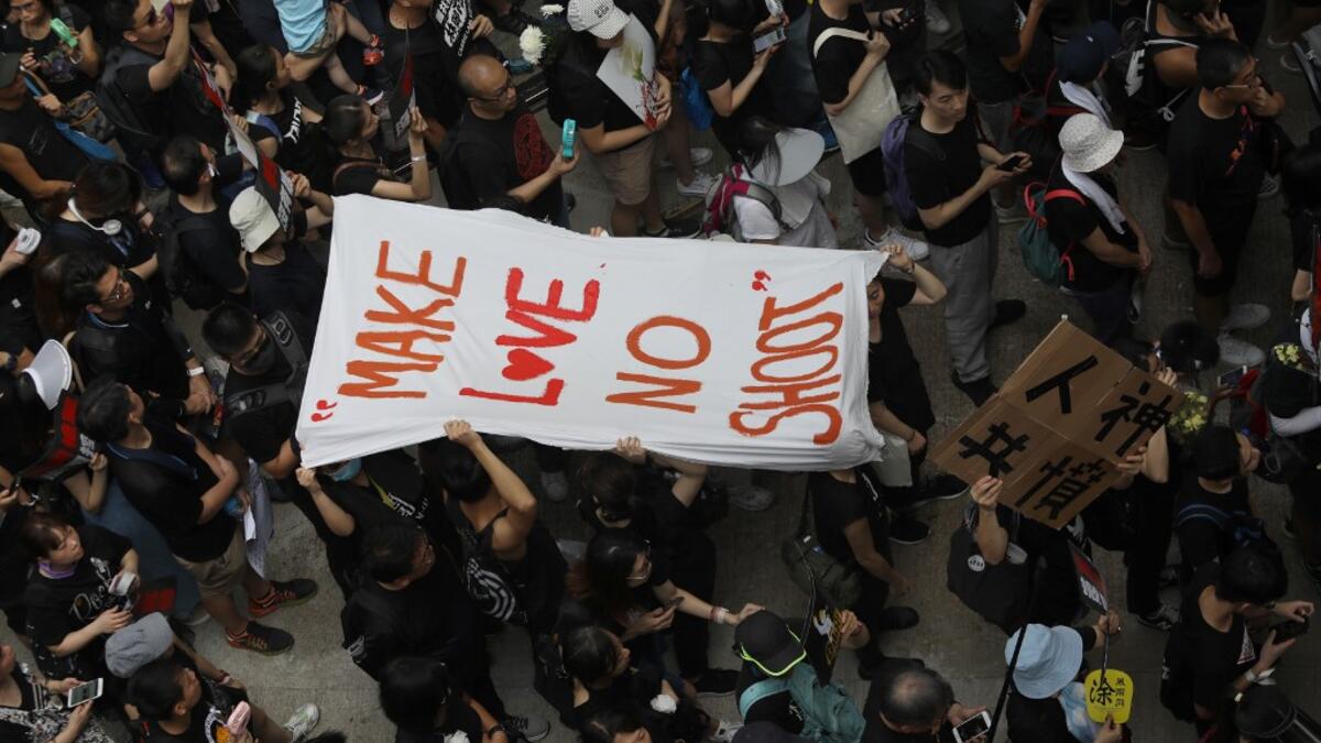 People carry a banner reading "Make love no shoot" in reference to police firing on protesters on June 12, as thousands of protesters dressed in black take part in a new rally against a controversial extradition law proposal in Hong Kong  Dale DE LA REY / AFP