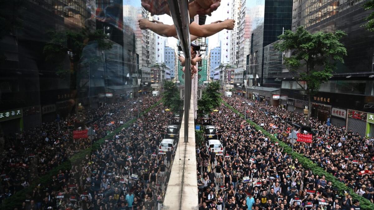 Thousands of protesters (R) dressed in black as reflected on the glass over a balcony (L) as they take part in a new rally against a controversial extradition law proposal in Hong Kong.  HECTOR RETAMAL / AFP