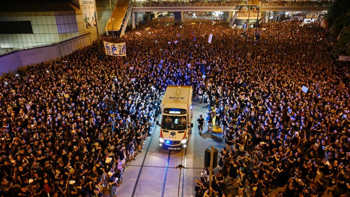 An ambulance is pictured surrounded by thousands of protesters dressed in black during a new rally against a controversial extradition law proposal in Hong Kong.  HECTOR RETAMAL / AFP