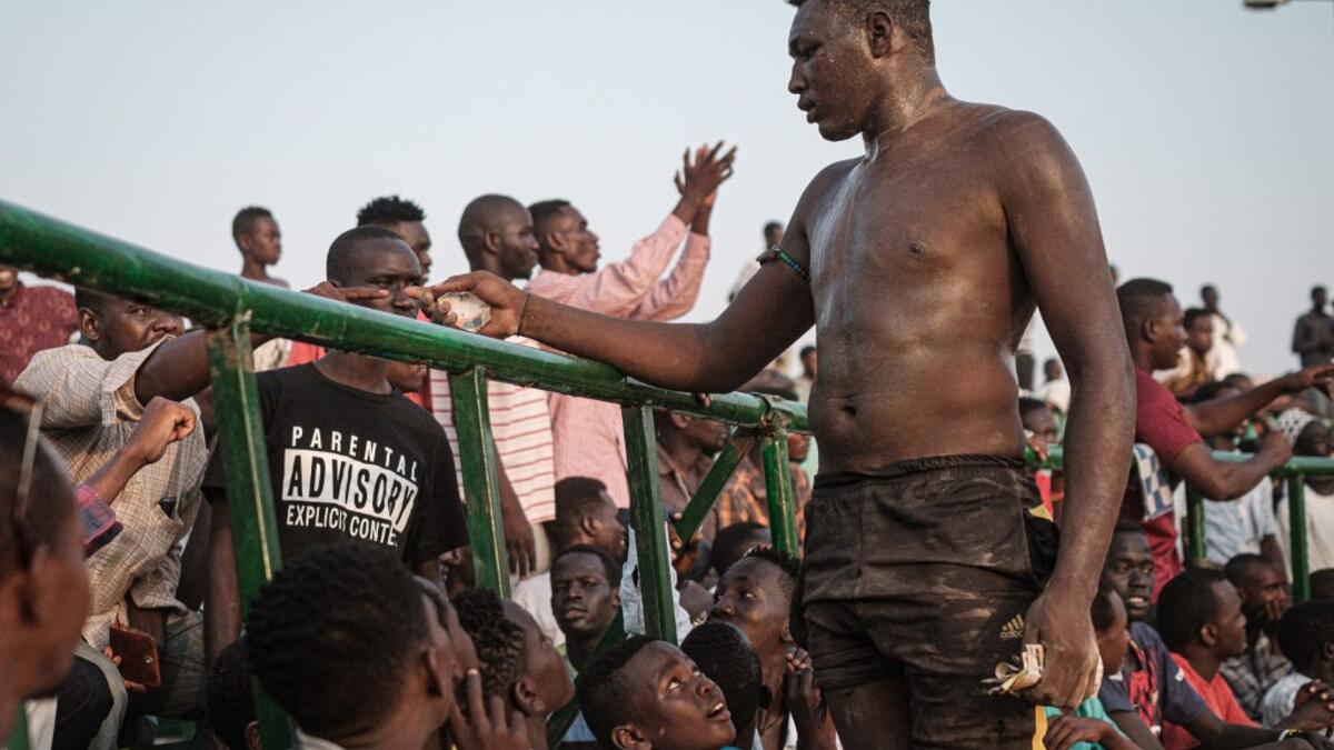 A Sudanese wrestler receives money from spectators after winning during a traditional Nuba wrestling match at the Haj Youssef stadium in the district of Khartoum.  Yasuyoshi CHIBA / AFP