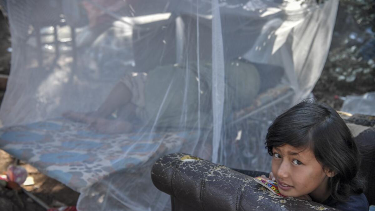 A girl gazes at the makeshift part of the Samos refugee camp, just above the island's capital city of Vathy.  LOUISA GOULIAMAKI / AFP