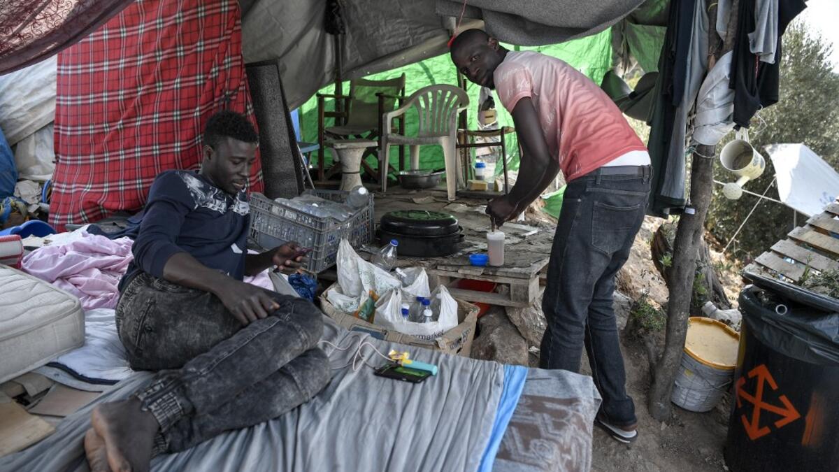 Migrants prepare tea at the makeshift refugee camp on the island of Samos just above the island's capital city of Vathy.  LOUISA GOULIAMAKI / AFP