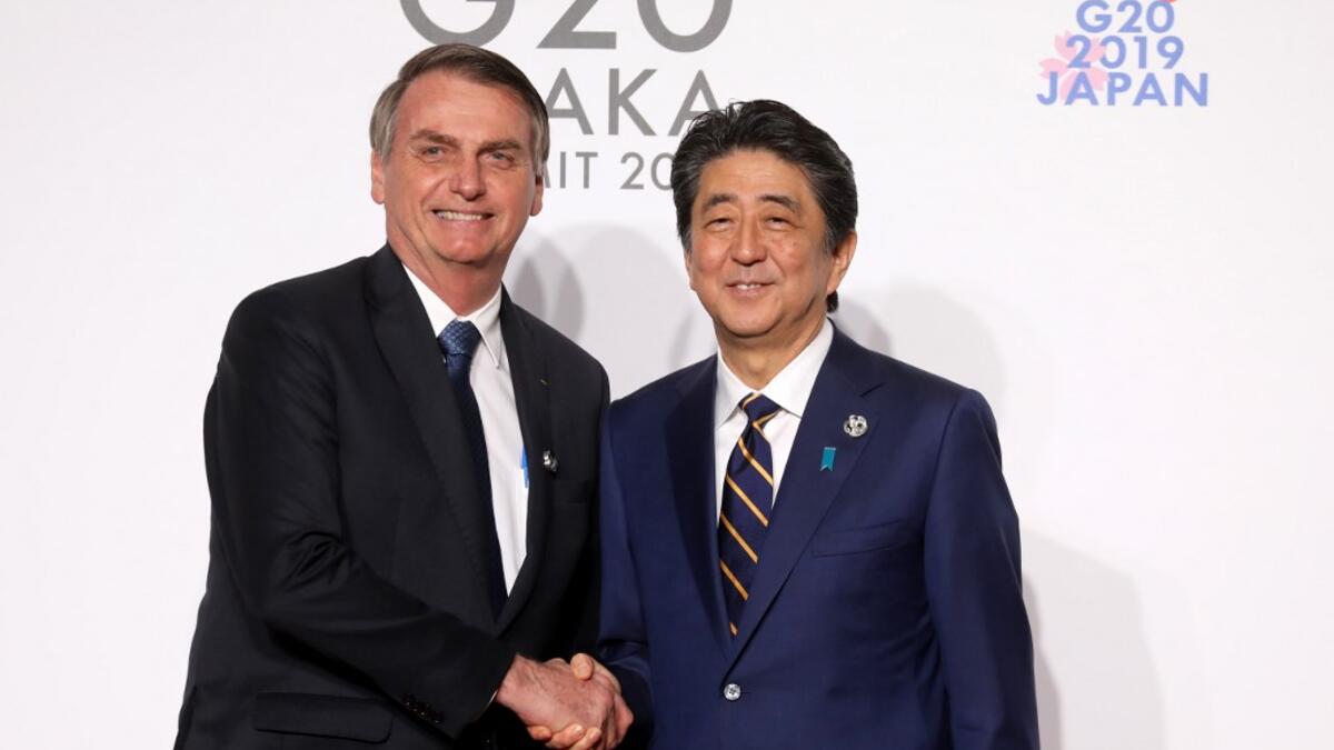 Brazil's President Jair Bolsonaro (L) is welcomed by Japan's Prime Minister Shinzo Abe to the G20 Summit in Osaka on June 28, 2019.  Ludovic MARIN / POOL / AFP