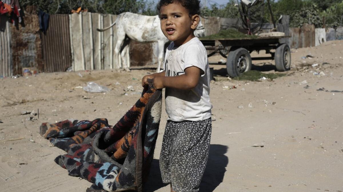 A Palestinian boy pulls a blanquet at an impoverished neighbourhood in Gaza City on July 4, 2019.  MOHAMMED ABED / AFP