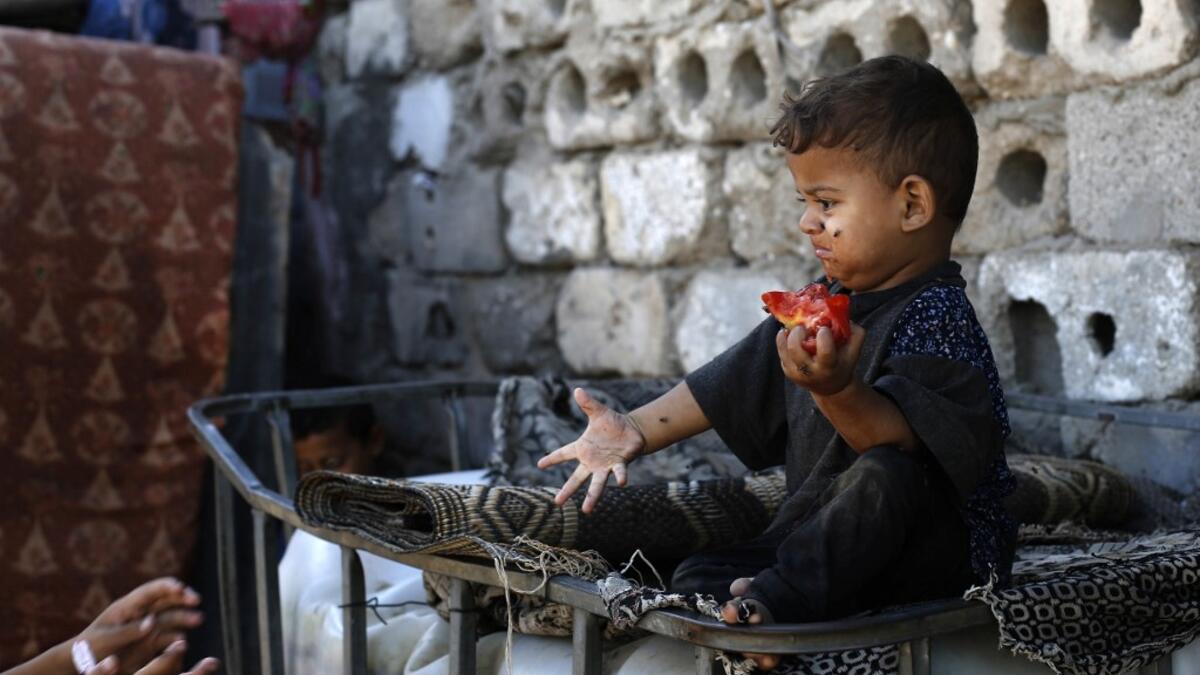 A Palestinian boy eats a tomato at an impoverished neighbourhood in Gaza City on July 4, 2019.  MOHAMMED ABED / AFP