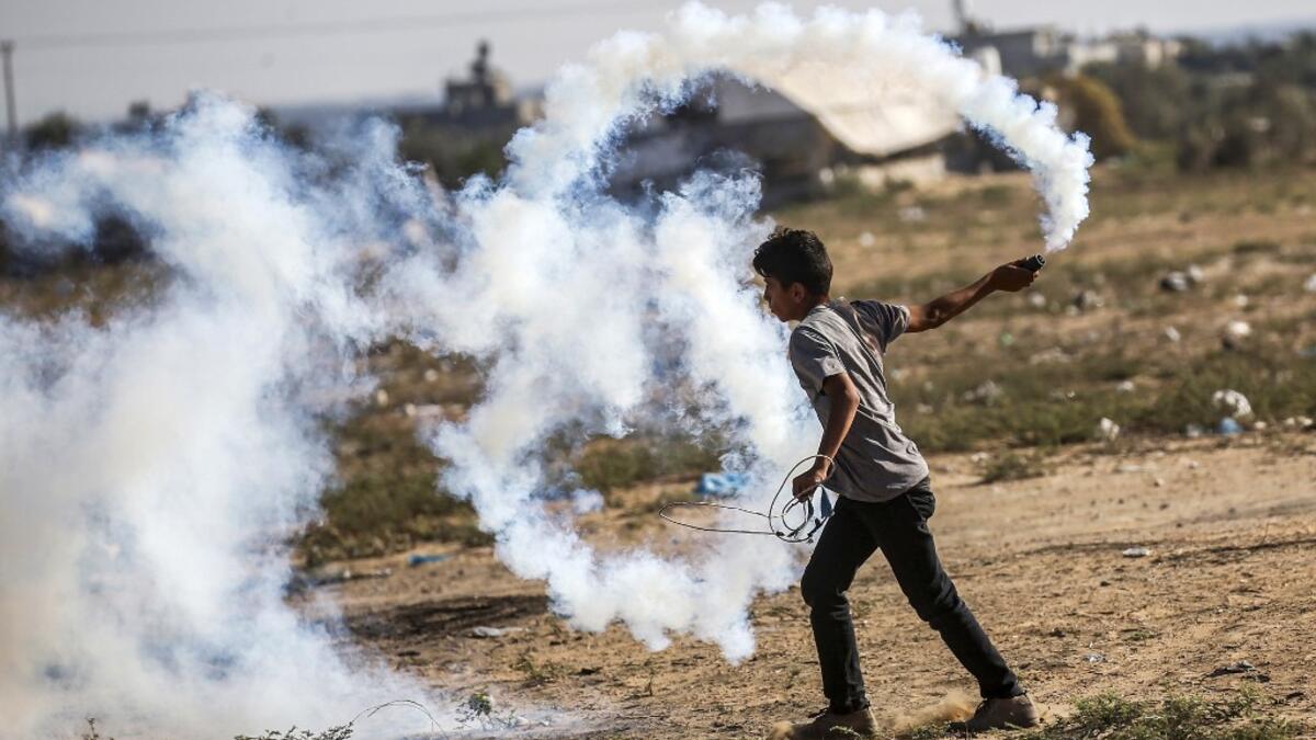 A Palestinian protester carries a tear gas canister to be thrown back at Israeli forces across the border during protests along the border with Israel east of Khan Yunis in the southern Gaza strip on July 5, 2019.  SAID KHATIB / AFP
