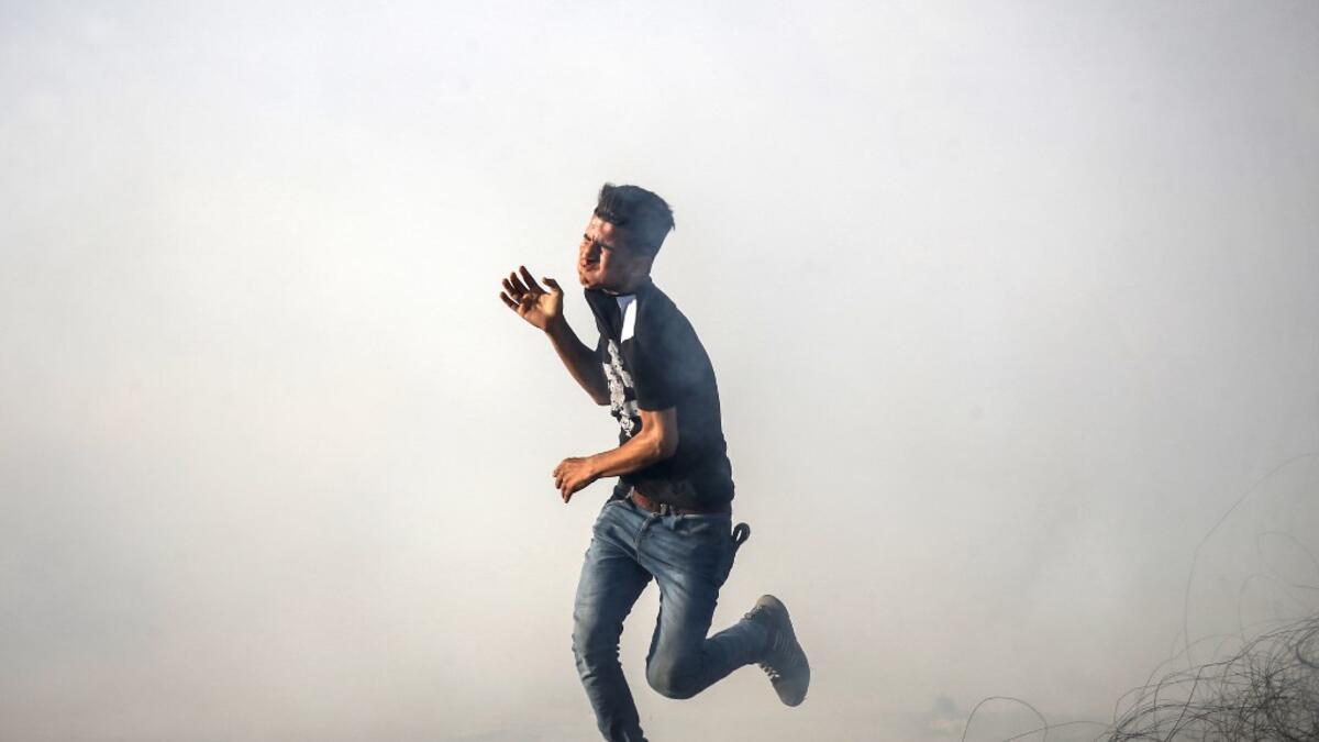 A Palestinian protester flees from tear gas fired by Israeli forces during protests along the border with Israel east of Khan Yunis in the southern Gaza strip on July 5, 2019.  SAID KHATIB / AFP