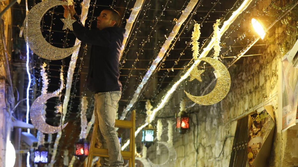 A Palestinian man decorates with lights near the entrance of the al-Aqsa mosque compound, in the old city of Jerusalem on May 4, 2019, as Muslims around the world prepare for the announcement of the fasting month of Ramadan. AHMAD GHARABLI / AFP