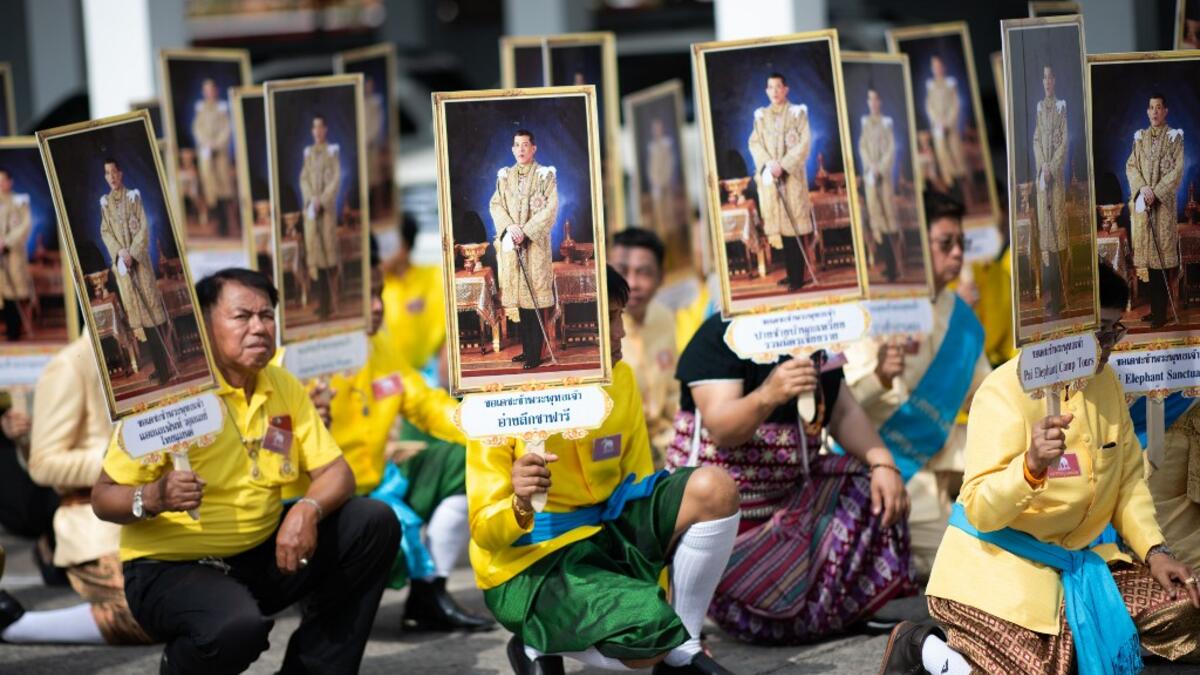 Well-wishers hold pictures of Thailand's King Maha Vajiralongkorn during a procession near the Grand Palace to pay their respects to the King in Bangkok on May 7, 2019.  Jewel SAMAD / AFP