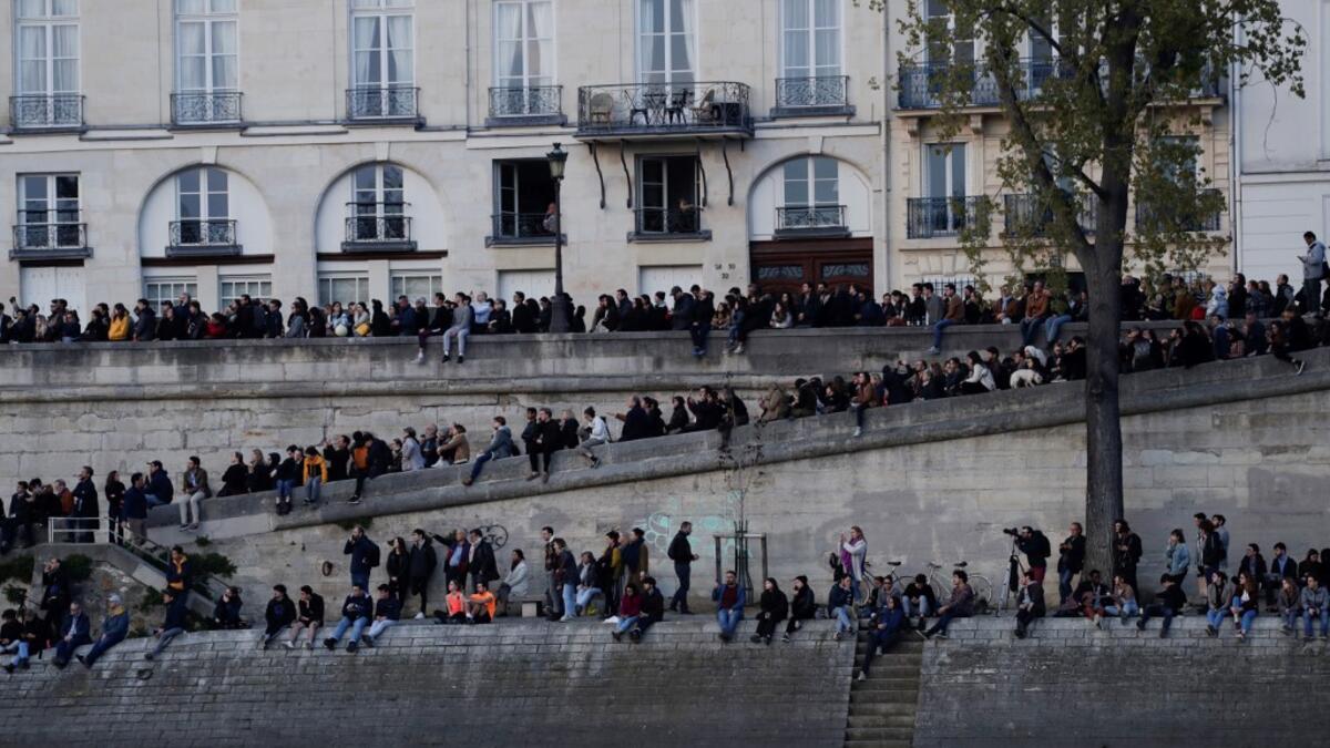 People look at the fire engulfing the Notre-Dame Cathedral in central Paris from the quai de la Tournelle on the banks of the Seine river on April 15, 2019. Geoffroy VAN DER HASSELT / AFP
