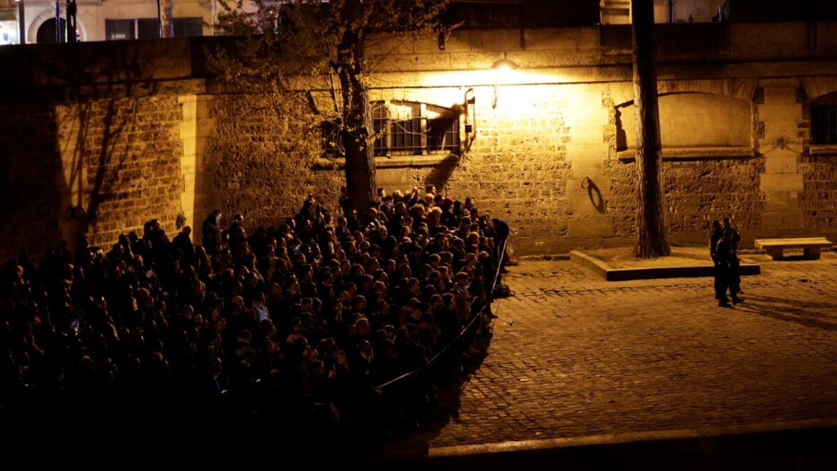 People look at the fire engulfing the Notre-Dame Cathedral in central Paris from the quai de la Tournelle on the banks of the Seine river on April 15, 2019. Geoffroy VAN DER HASSELT / AFP