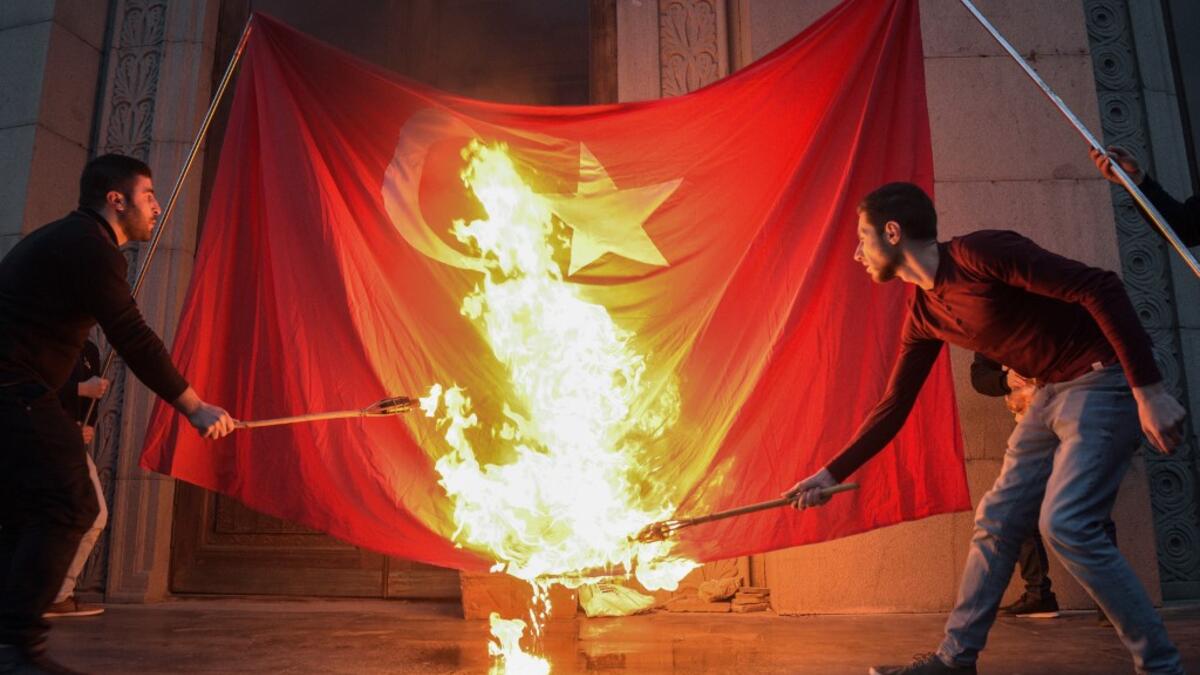 Men burn a Turkish flag ahead of a torchlight procession as they mark the anniversary of the killing of 1.5 million Armenians by Ottoman forces, Yerevan, April 23, 2019. KAREN MINASYAN / AFP