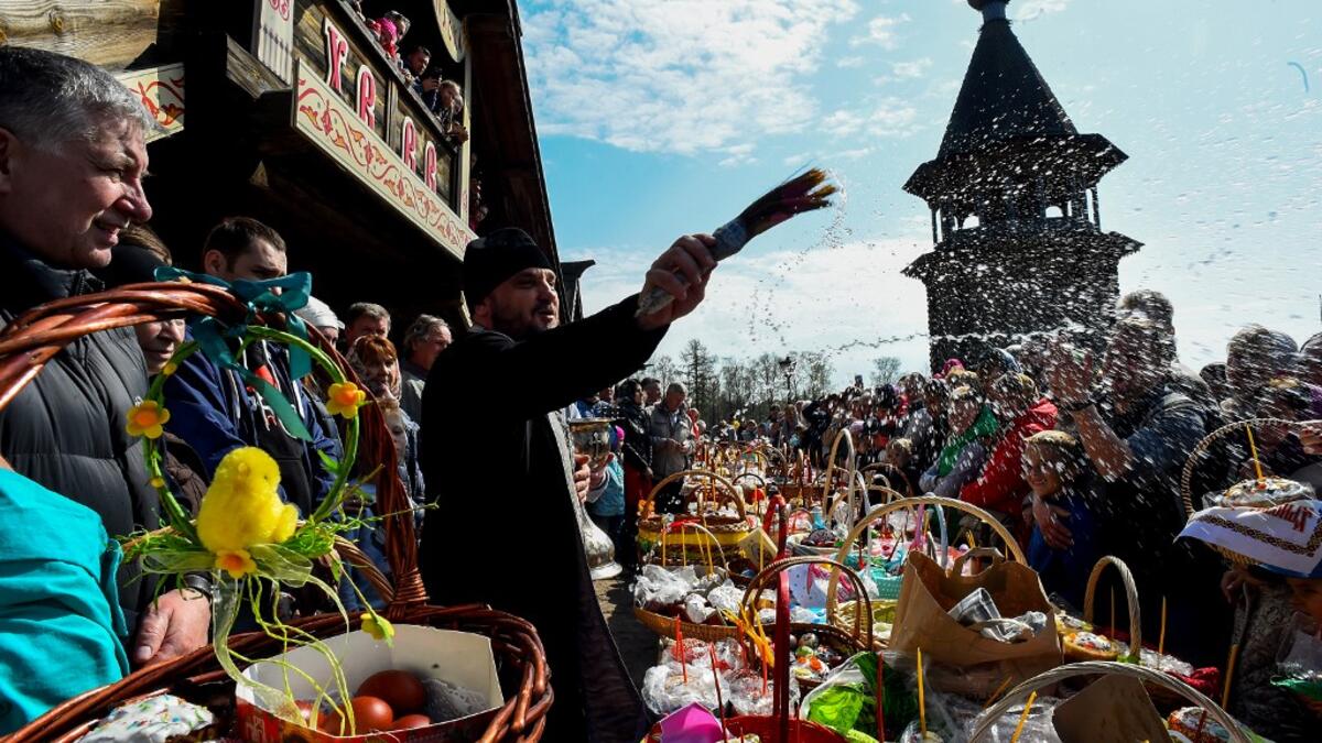 An Orthodox priest blesses traditional cakes and eggs on the eve of Orthodox Easter at Saint Petersburg's Pokrovsky Cathedral on April 27, 2019.  Olga MALTSEVA / AFP