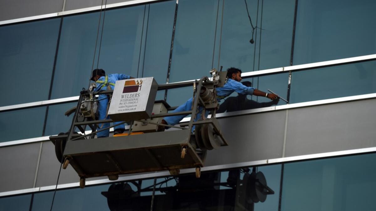 Pakistani labourers clean the windows of a bulding in Karachi on April 30, 2019, on the eve of the International Labour Day celebrated on May 1.  RIZWAN TABASSUM / AFP