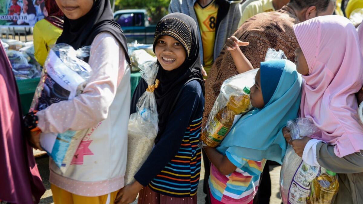 Thai Muslim girls carry bags of rice and food donated by the local government during a ceremony ahead of the Islamic holy month of Ramadan in the southern Thai province of Narathiwat on May 4, 2019.  Madaree TOHLALA / AFP