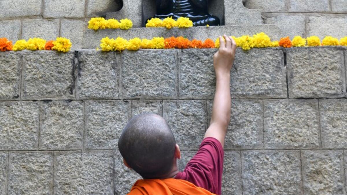 A young Buddhist monk decorates a stupa with flowers during "Vesak" or Buddha Purnima to commemorate the 2,563rd birth anniversary of the Buddha, at the Maha Bodhi Society in Bangalore on May 18, 2019. MANJUNATH KIRAN / AFP