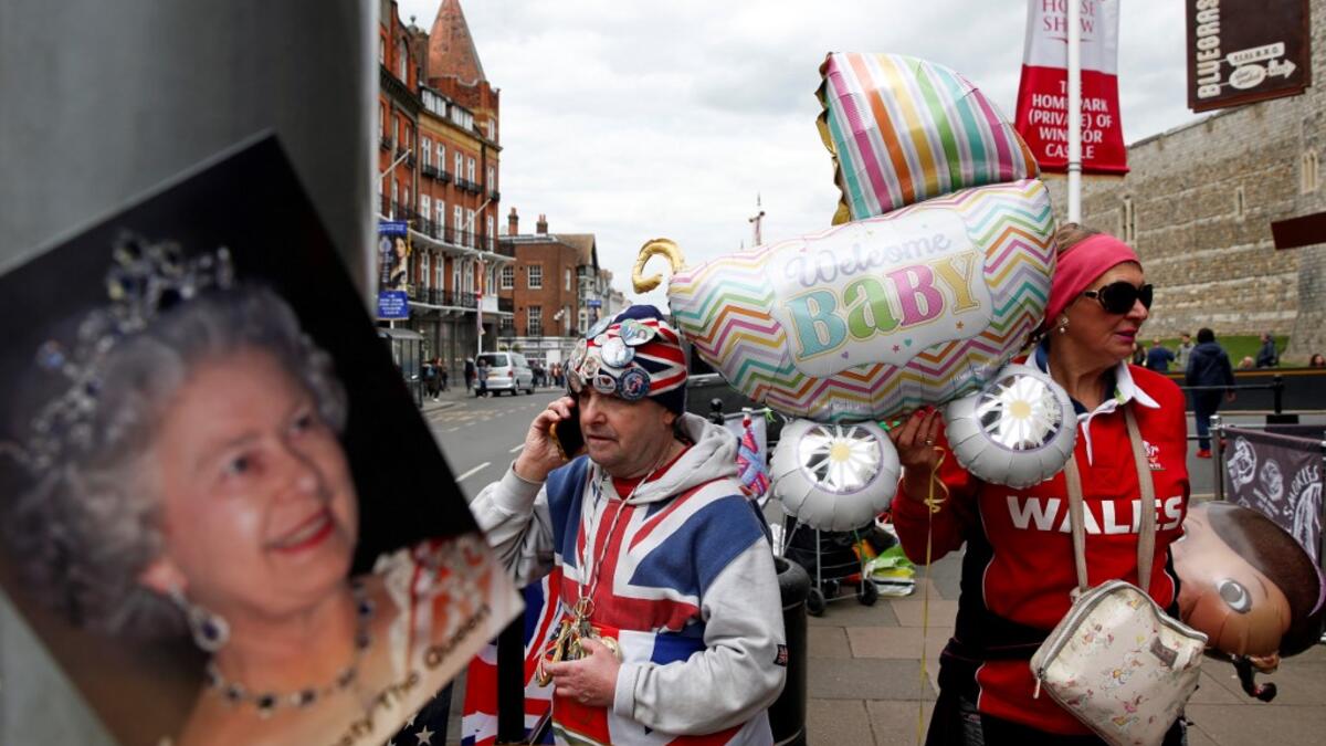 Royal super fans John Loughery (L) and Anne Daley stand near Windsor Castle, west of London on May 6, 2019, with baby-themed items as they wait for news of the imminent birth of the child of Britain's Prince Harry and Meghan, Duke and Duchess of Sussex.  ADRIAN DENNIS / AFP